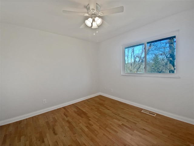 spare room featuring visible vents, baseboards, and wood finished floors