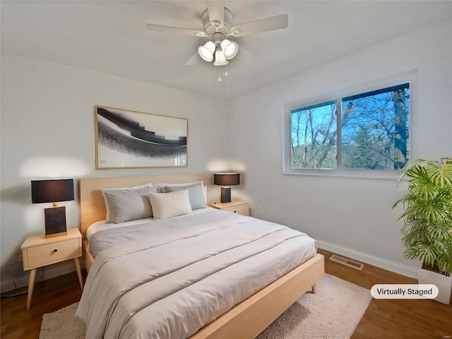 bedroom with visible vents, baseboards, wood finished floors, and a ceiling fan