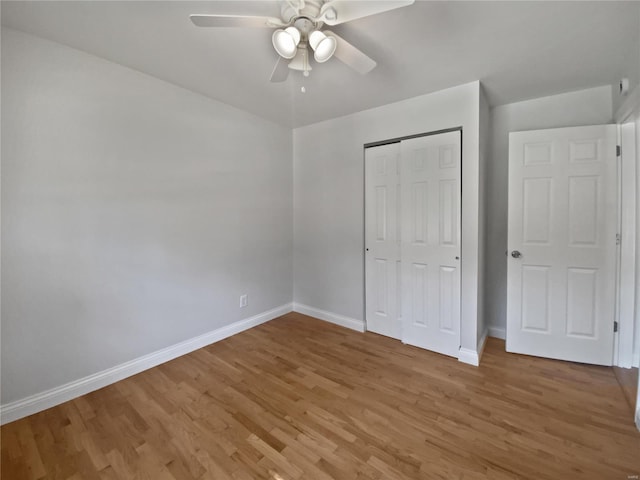 unfurnished bedroom with a closet, ceiling fan, light wood-type flooring, and baseboards