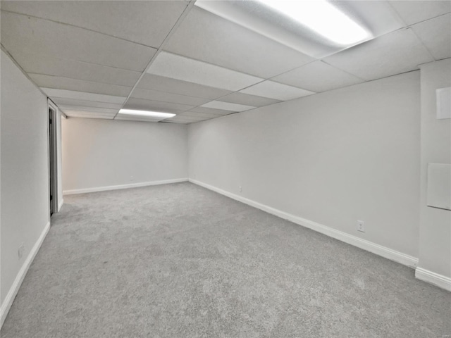 finished basement with carpet flooring, a paneled ceiling, and baseboards