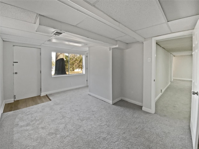 carpeted spare room with baseboards, visible vents, and a drop ceiling