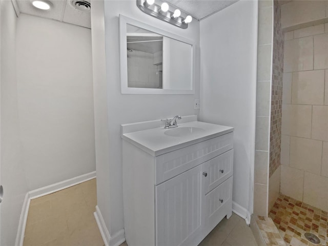 bathroom featuring visible vents, tiled shower, vanity, and baseboards