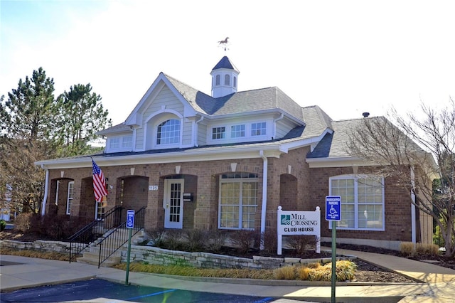 view of front of home featuring brick siding and a shingled roof