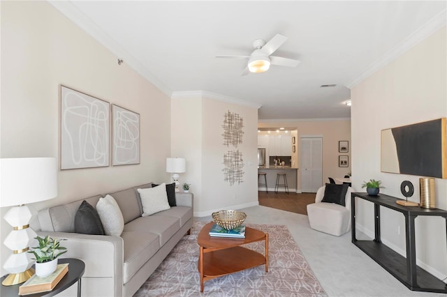 living area featuring baseboards, carpet floors, ceiling fan, and crown molding