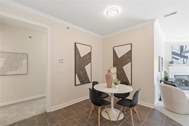 dining area featuring visible vents, baseboards, a fireplace, and crown molding