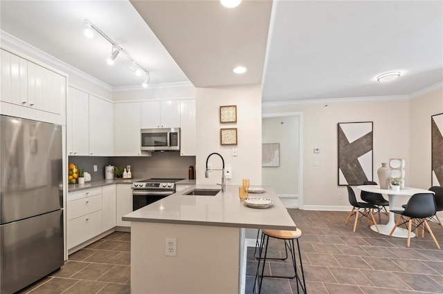 kitchen with crown molding, a breakfast bar area, appliances with stainless steel finishes, a peninsula, and a sink