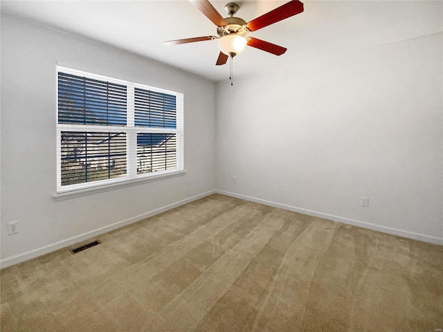 unfurnished room with visible vents, baseboards, light colored carpet, and a ceiling fan