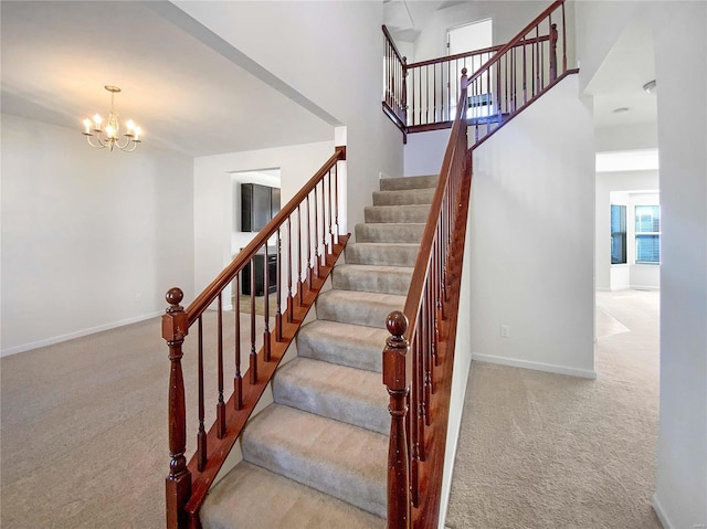 stairway featuring a chandelier, baseboards, and carpet floors