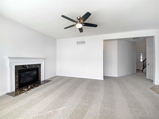 unfurnished living room with visible vents, a ceiling fan, carpet, a premium fireplace, and stairs