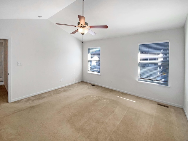 spare room with baseboards, visible vents, carpet floors, ceiling fan, and vaulted ceiling