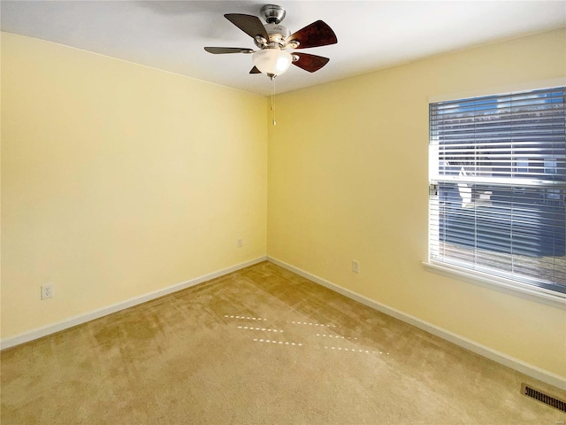 empty room featuring visible vents, baseboards, carpet, and a ceiling fan