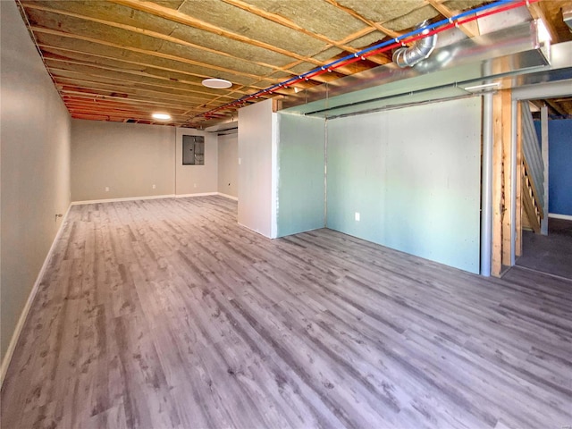 unfinished basement featuring electric panel, baseboards, and wood finished floors