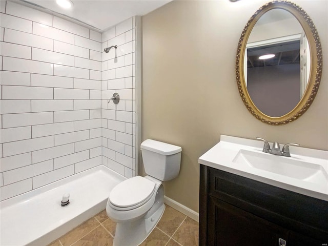 bathroom featuring vanity, baseboards, a tile shower, tile patterned floors, and toilet