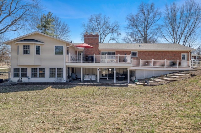 rear view of house with brick siding, a lawn, a chimney, and a patio