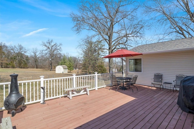 wooden terrace with a storage unit, an outbuilding, and outdoor dining space