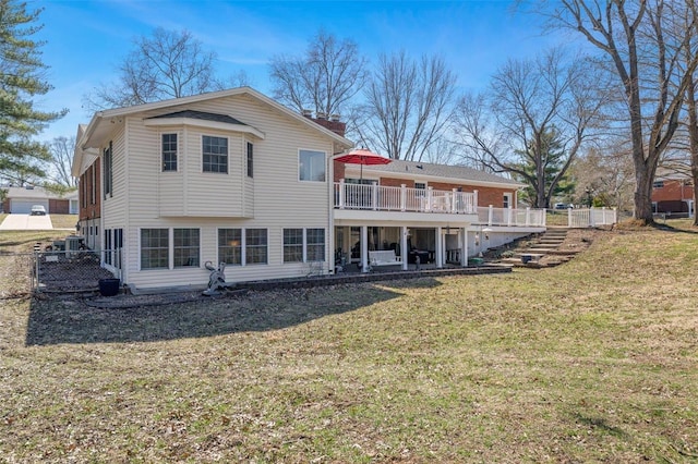 back of house featuring a deck, a chimney, a yard, and fence