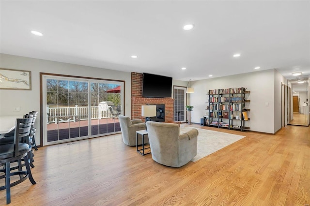 living room featuring recessed lighting, a fireplace, and light wood-style floors