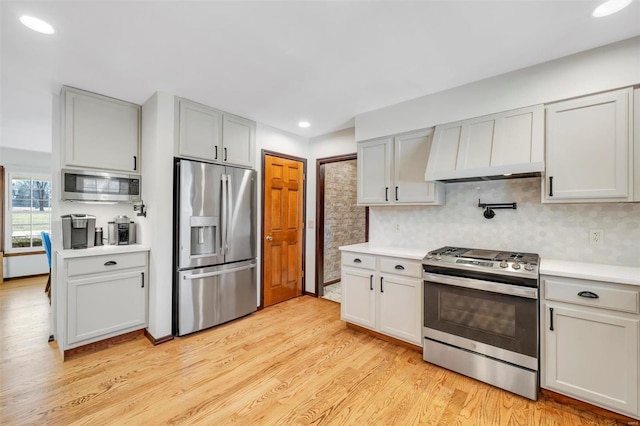 kitchen with light wood finished floors, tasteful backsplash, premium range hood, light countertops, and stainless steel appliances