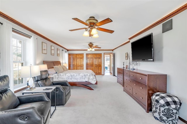 bedroom featuring light carpet, a ceiling fan, multiple closets, and ornamental molding