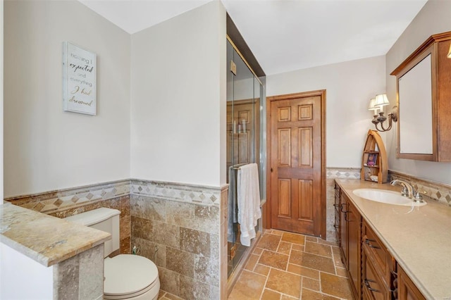 full bathroom with toilet, tile walls, stone tile flooring, and vanity