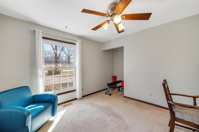 living area featuring visible vents, baseboards, ceiling fan, and carpet flooring