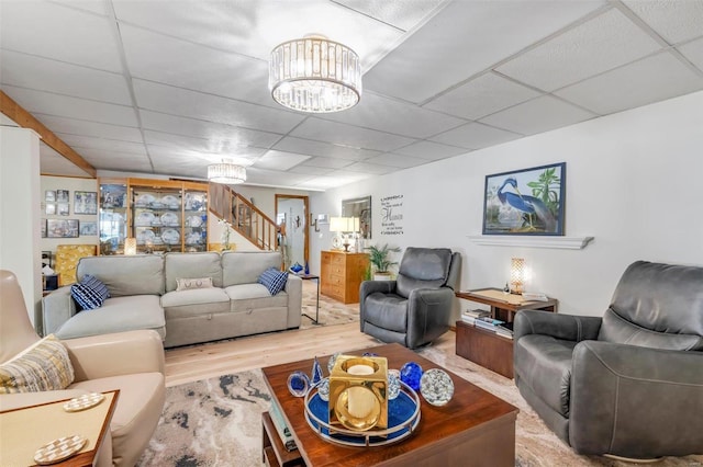 living room featuring stairway, a paneled ceiling, and wood finished floors