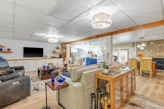 living room with light wood-type flooring, a paneled ceiling, and a chandelier