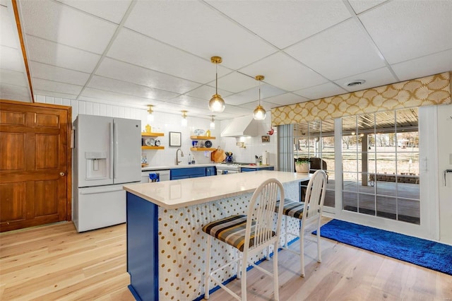 kitchen with a drop ceiling, light wood-style flooring, white appliances, and light countertops