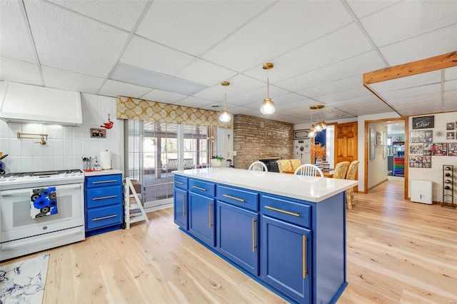 kitchen with white range with gas cooktop, blue cabinetry, light wood-style floors, and premium range hood