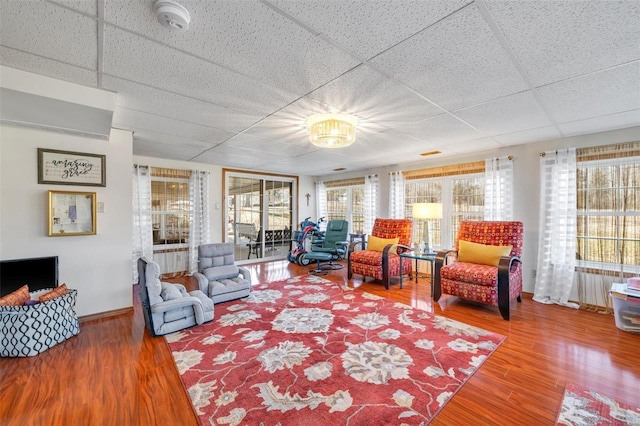 living area featuring wood finished floors and a paneled ceiling