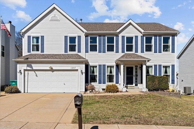 colonial home with a shingled roof, concrete driveway, central AC, a front yard, and a garage