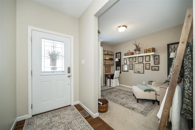 foyer entrance featuring dark wood-type flooring, visible vents, and baseboards