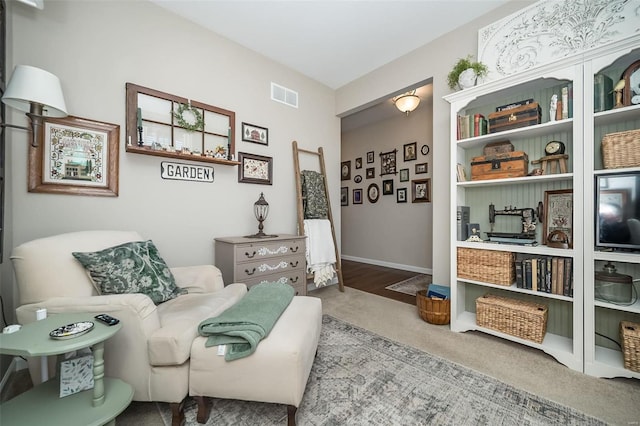 living area featuring visible vents, baseboards, and carpet floors