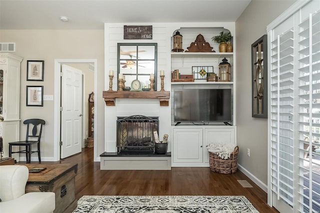 living room featuring visible vents, a large fireplace, dark wood-type flooring, and baseboards