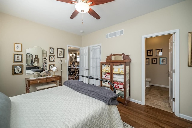 bedroom featuring dark wood-style floors, visible vents, ceiling fan with notable chandelier, and baseboards