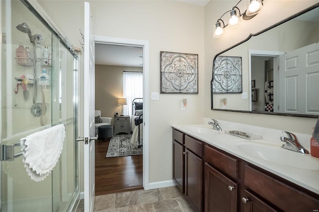 ensuite bathroom featuring double vanity, a stall shower, and a sink