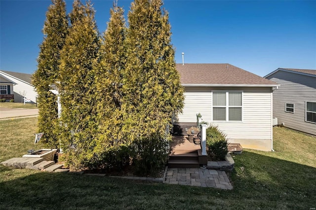 back of property with a deck, a lawn, and roof with shingles