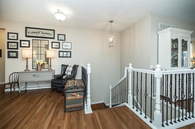 interior space featuring visible vents, baseboards, wood finished floors, and a chandelier