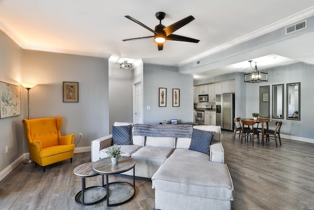 living area with visible vents, wood finished floors, baseboards, and ornamental molding