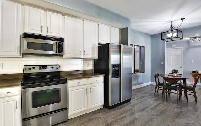 kitchen with dark countertops, stainless steel appliances, white cabinets, decorative backsplash, and dark wood-style flooring