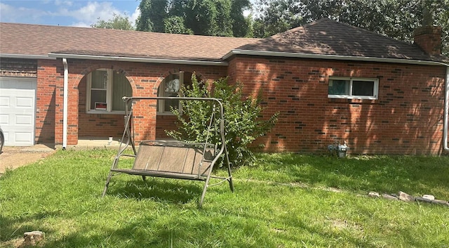 back of house with roof with shingles, an attached garage, a chimney, a lawn, and brick siding