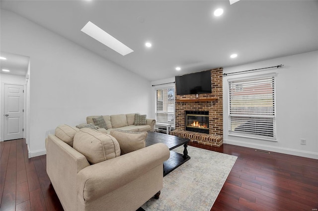 living area with lofted ceiling with skylight, a fireplace, baseboards, and hardwood / wood-style flooring