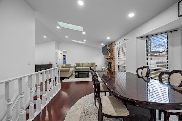 dining area with recessed lighting, vaulted ceiling with skylight, dark wood-style floors, and a fireplace