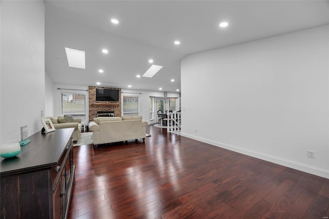 living area featuring dark wood-type flooring, a brick fireplace, recessed lighting, and lofted ceiling with skylight