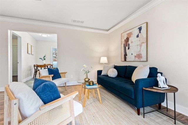 living area with visible vents, baseboards, wood finished floors, and crown molding