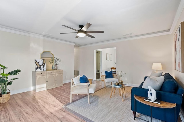 sitting room featuring visible vents, baseboards, ornamental molding, light wood-style flooring, and a ceiling fan