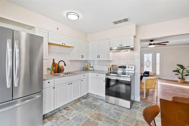 kitchen featuring visible vents, a sink, under cabinet range hood, tasteful backsplash, and stainless steel appliances