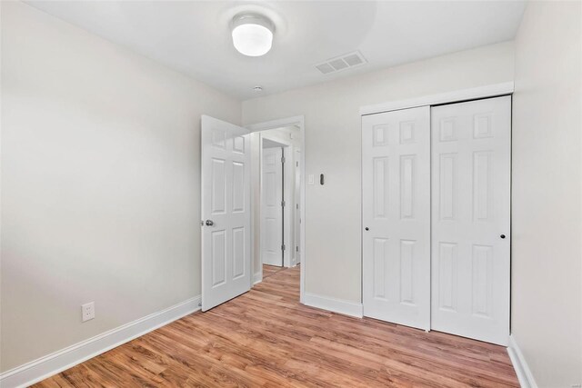 unfurnished bedroom with a closet, visible vents, baseboards, and light wood-style floors