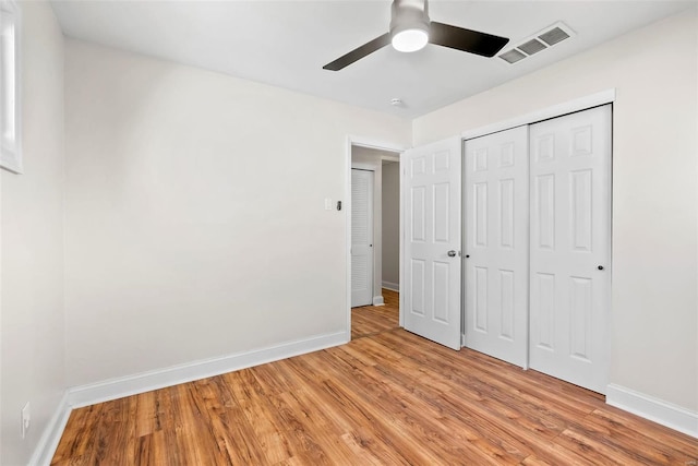 unfurnished bedroom featuring light wood-type flooring, visible vents, baseboards, and a closet