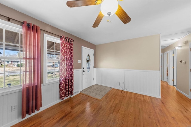 unfurnished room featuring a wainscoted wall, light wood-style floors, and ceiling fan